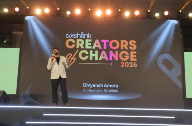 Speaker on a brightly lit stage delivering a talk at Creators of Change 2026 (Wishlink), with a colorful backdrop reading ‘Creators of Change 2026’.