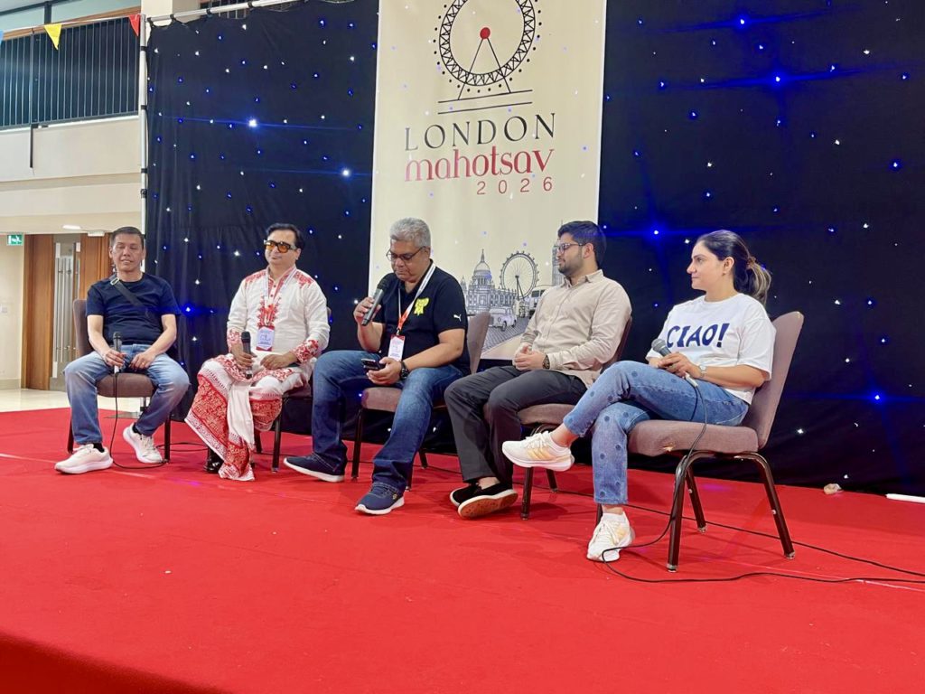 b19192ea-1894-4af3-83e0-92aede801302 - Social Nation Five panelists seated on a red stage with microphones, a London Mahotsav 2026 banner behind them, and blue starry backdrop.